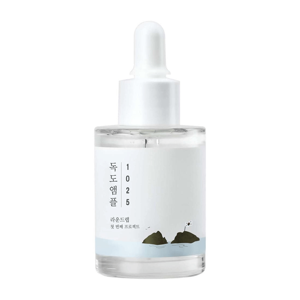 Une bouteille transparente avec 1025 Dokdo Ampoule sérum pour le visage, décorée d'un thème marin minimaliste, sur fond blanc.