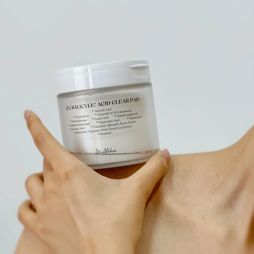 Dr. Althea 2% Salicylic Acid Clear Pad tenu à la main. Tampons tonifiants avec 2% d'acide salicylique qui exfolient doucement, apaisent la peau et améliorent la texture de la peau.