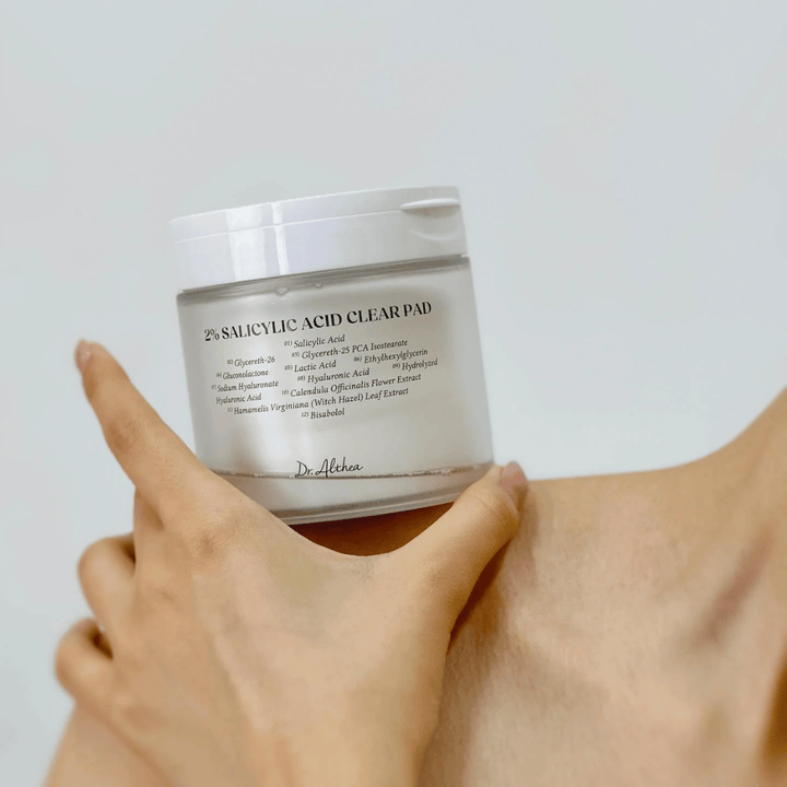 Dr. Althea 2% Salicylic Acid Clear Pad tenu à la main. Tampons tonifiants avec 2% d'acide salicylique qui exfolient doucement, apaisent la peau et améliorent la texture de la peau.