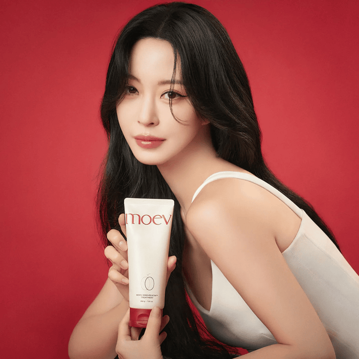 Kvinna med långt, glänsande hår håller MOEV Annurcatin Treatment – koreansk hårvård som ger näring, styrka och glans med naturliga ingredienser.