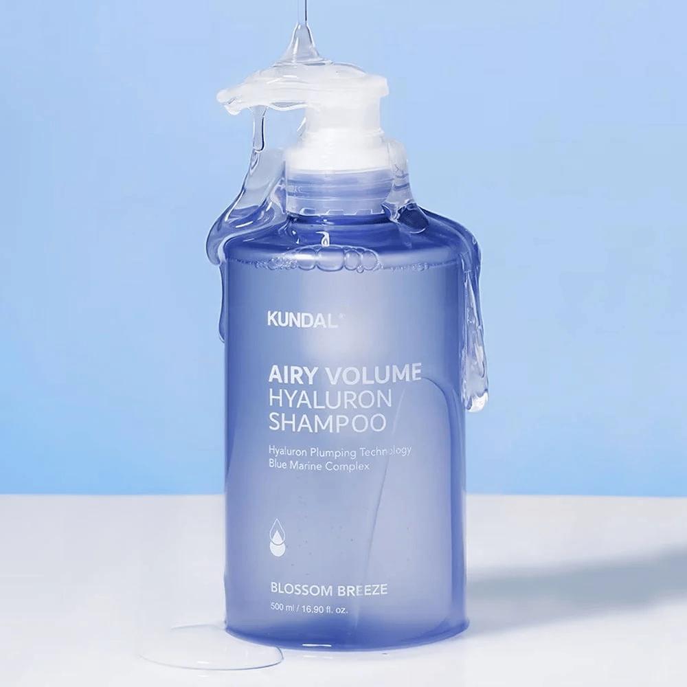 KUNDAL Airy Volume Hyaluron Shampoo Blossom Breeze i blå pumpflaska, med hyaluron och Blue Marine Complex, fotograferad med rinnande vatten.