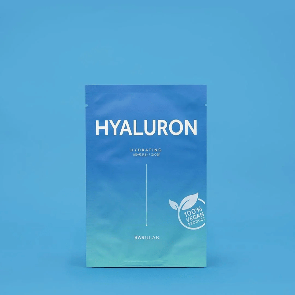 Un emballage de BARULAB masque "HYALURON Hydrating", marqué comme "100% Produit Végétalien", devant un fond bleu uniforme. L'emballage a un dégradé de couleur du bleu foncé au bleu clair.