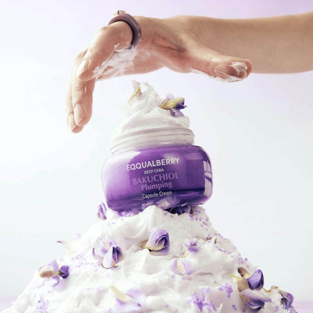 EQQUALBERRY Bakuchiol Plumping Capsule Cream placé sur un tas de crème fouettée avec des pétales de fleurs – symbolise l'hydratation et le soin.