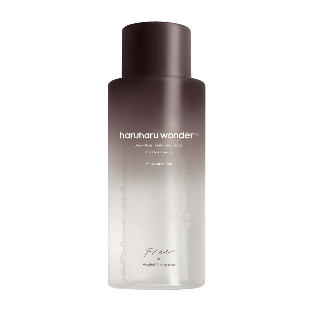 Une bouteille de haruharu wonder Black Rice Hyaluronic Toner The First Essence, avec un dégradé de brun foncé à transparent et le texte "Sans alcool et sans parfum", sur fond blanc.