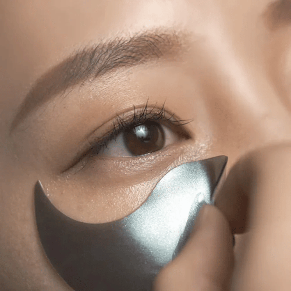 Image détaillée montrant l’application d’un patch contour des yeux en hydrogel noir sous l’œil. L’image montre l’ajustement parfait et la sensation rafraîchissante autour du contour des yeux.