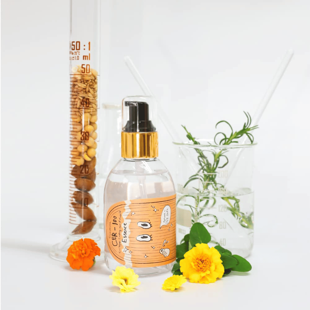 CER-100 Hair Essence avec des fleurs et du verre de laboratoire mettant en valeur les ingrédients et le soin capillaire.