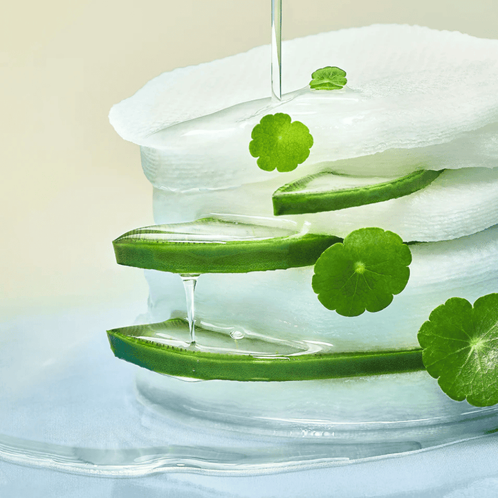 Gros plan sur des tranches d’aloe vera, des pads toner hydratant et des feuilles de centella asiatica. Le gel goutte entre les ingrédients pour illustrer les propriétés apaisantes, rafraîchissantes et hydratantes.