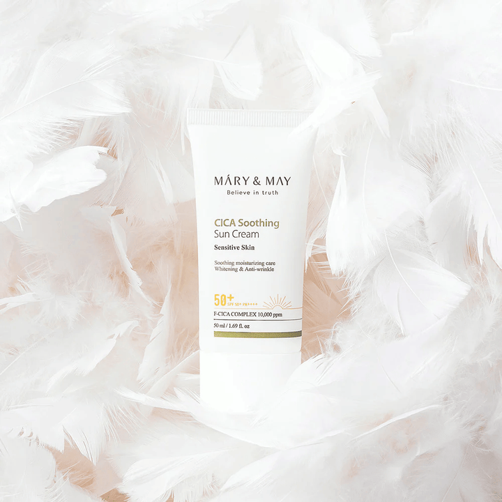 Mary&May CICA Soothing Sun Cream entouré de douces plumes blanches. L’image transmet une sensation de douceur, de confort et de formule légère adaptée aux peaux sensibles.