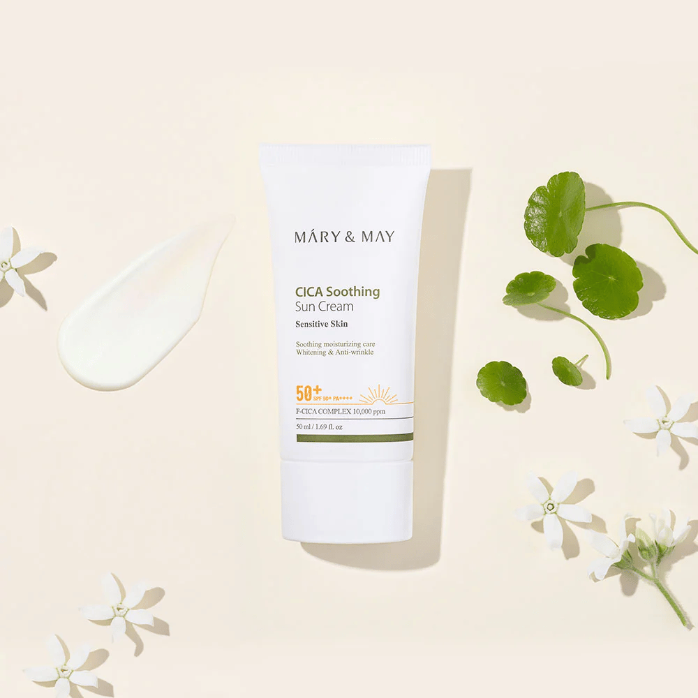 Mary&May CICA Soothing Sun Cream SPF50+ PA++++ présenté avec une texture de crème, des feuilles de centella et des fleurs blanches. L’image met en avant les propriétés apaisantes du produit et son accent sur les peaux sensibles.