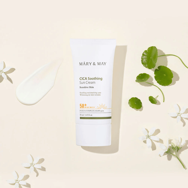 Mary&May CICA Soothing Sun Cream SPF50+ PA++++ présenté avec une texture de crème, des feuilles de centella et des fleurs blanches. L’image met en avant les propriétés apaisantes du produit et son accent sur les peaux sensibles.