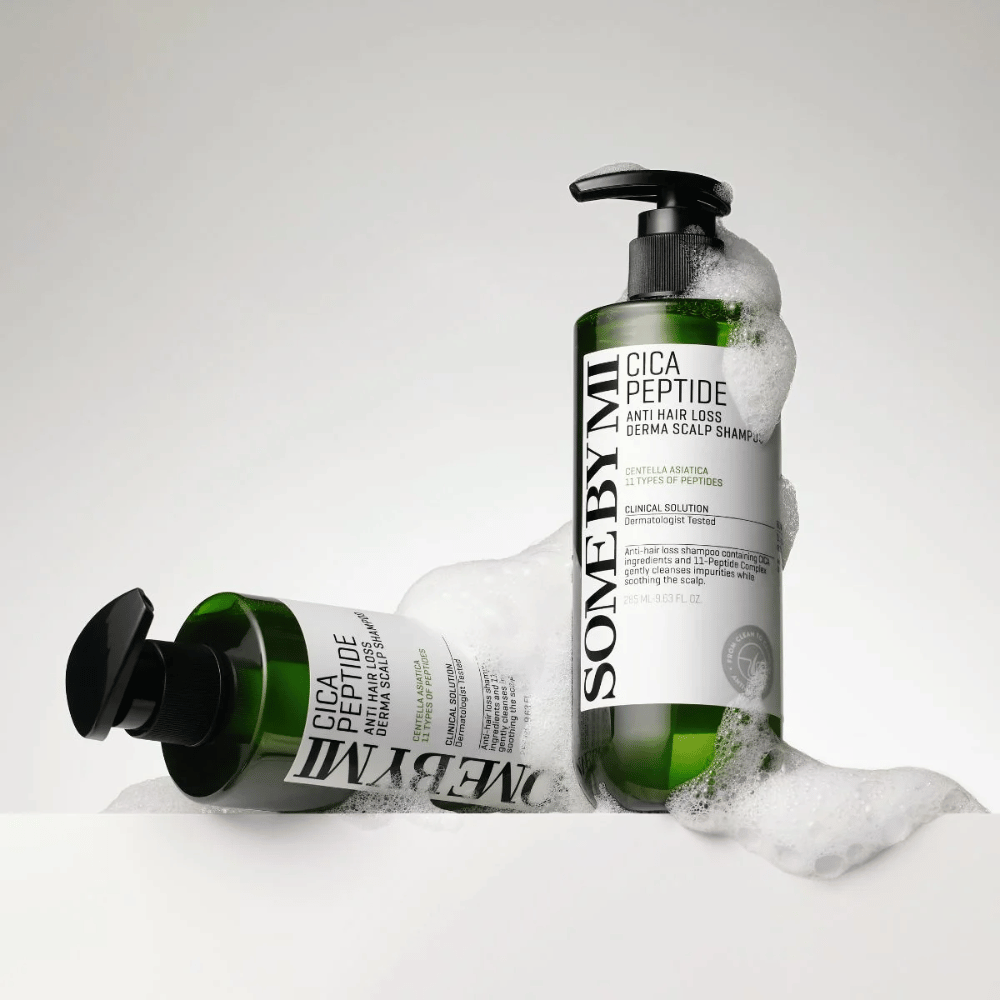 Deux bouteilles de SOME BY MI Cica Peptide Anti Hair Loss Derma Scalp Shampoo couvertes de mousse, debout et allongées sur un fond blanc.
