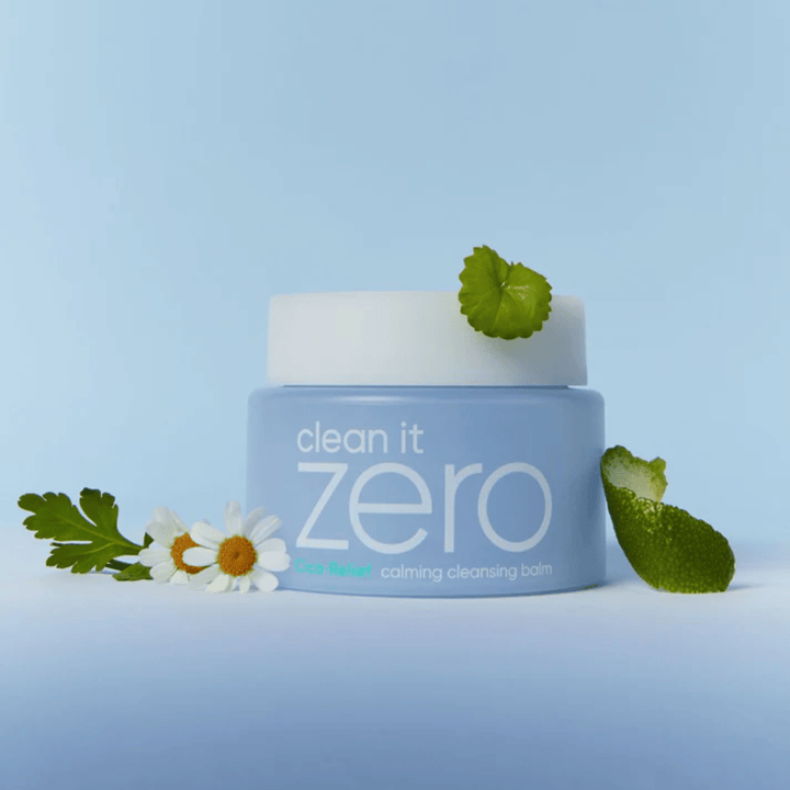Clean It Zero Cica-Relief Calming Cleansing Balm placé avec des plantes et des fleurs, illustrant un nettoyage doux avec CICA apaisant pour les peaux sensibles et irritées.