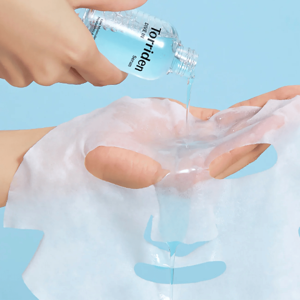 Masque facial dr imbibé de solution d'une bouteille "Torriden Dive-In", sur fond bleu.