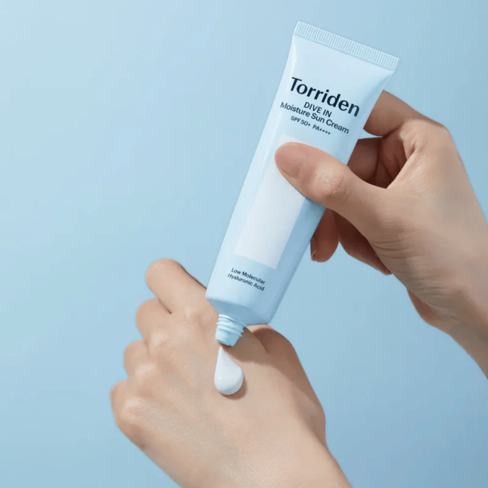 Torriden DIVE-IN Moisture Sun Cream SPF50+ PA++++ appliqué sur la main pour montrer la texture légère et crémeuse de la crème solaire hydratante.