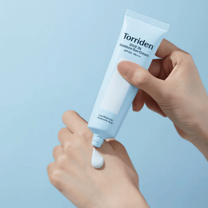Torriden DIVE-IN Moisture Sun Cream SPF50+ PA++++ appliqué sur la main pour montrer la texture légère et crémeuse de la crème solaire hydratante.