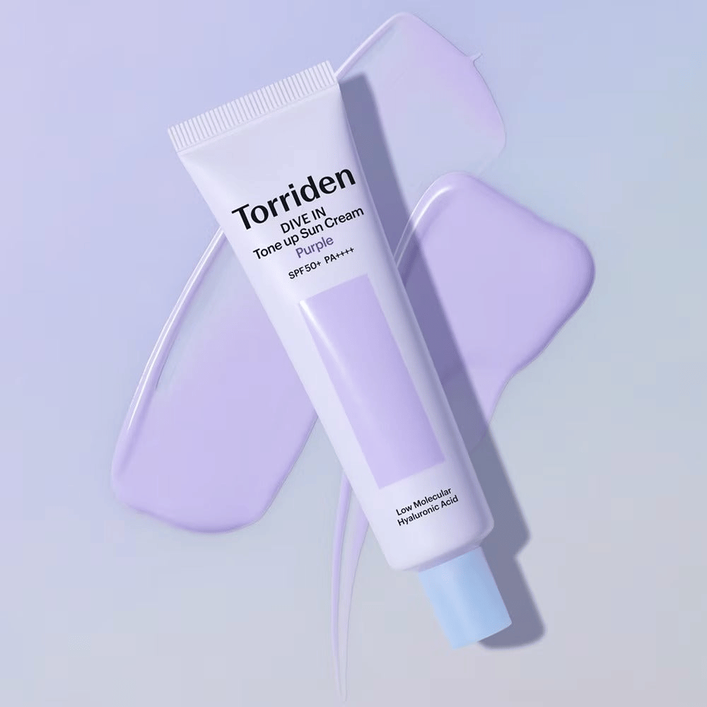 Torriden DIVE IN Tone Up Sun Cream Purple placé sur une crème violette étalée qui met en avant l’effet unifiant et éclatant.