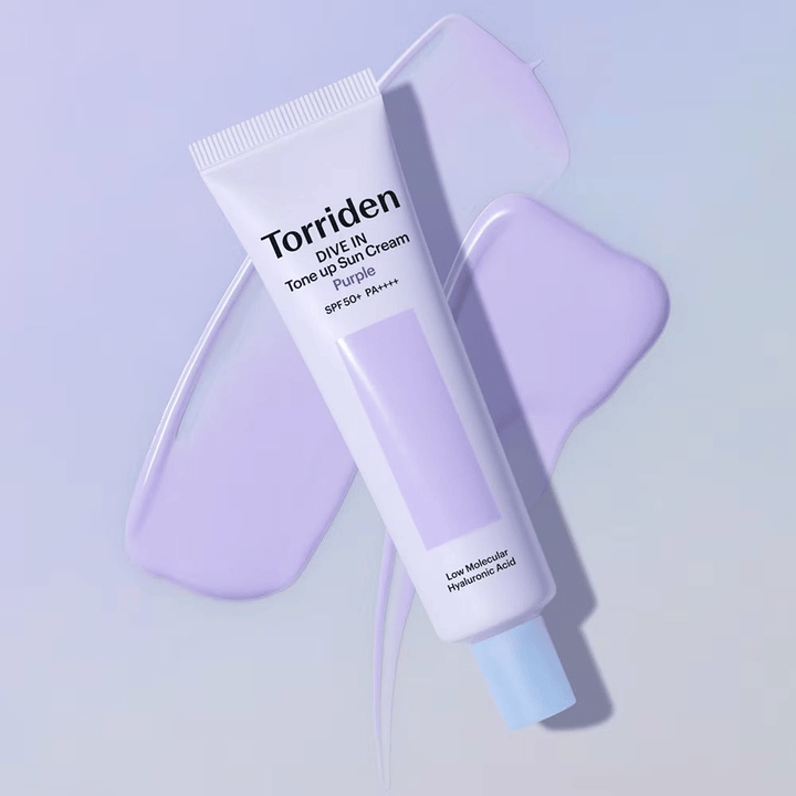Torriden DIVE IN Tone Up Sun Cream Purple placé sur une crème violette étalée qui met en avant l’effet unifiant et éclatant.