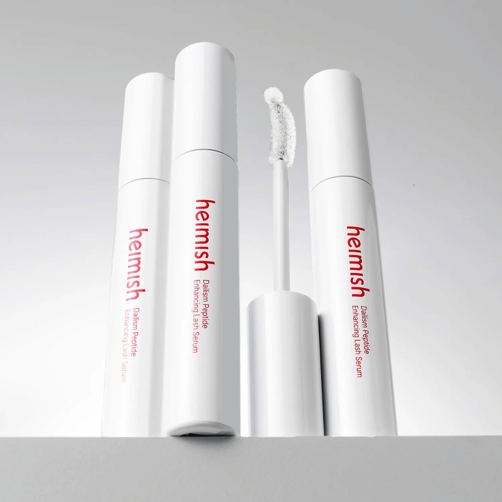 Plusieurs emballages de Heimish Dailism Peptide Enhancing Lash Serum sont présentés avec la brosse applicatrice incurvée. L’image met en valeur le design élégant du produit et sa brosse de précision pour une application facile.