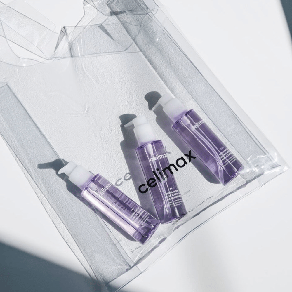 Tre flaskor av Celimax Derma Nature Fresh Blackhead Jojoba Cleansing Oil i lila förpackning, placerade i en transparent påse med logotypen 'celimax'.