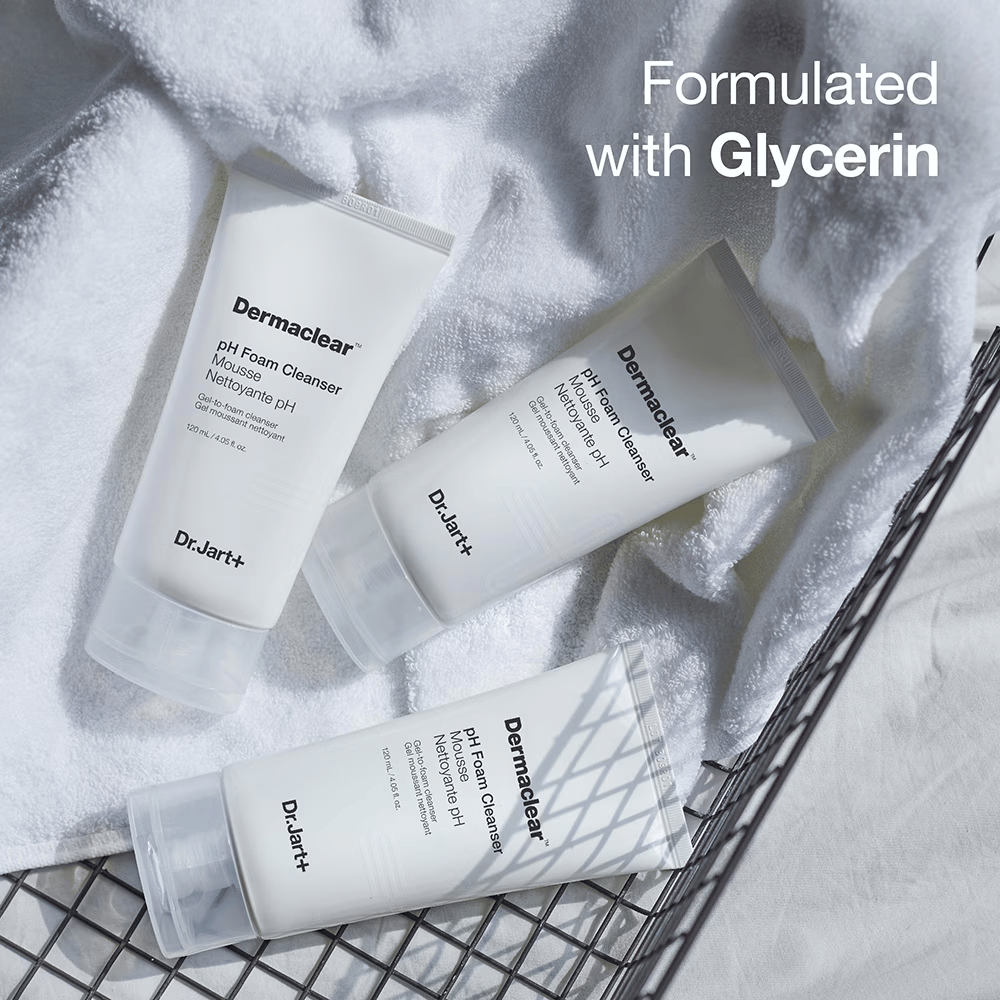 Trois tubes de Dr.Jart+ Dermaclear pH Foam Cleanser reposent sur une serviette en éponge blanche dans un panier en métal, avec le texte "Formulé avec Glycérine" dans le coin supérieur.