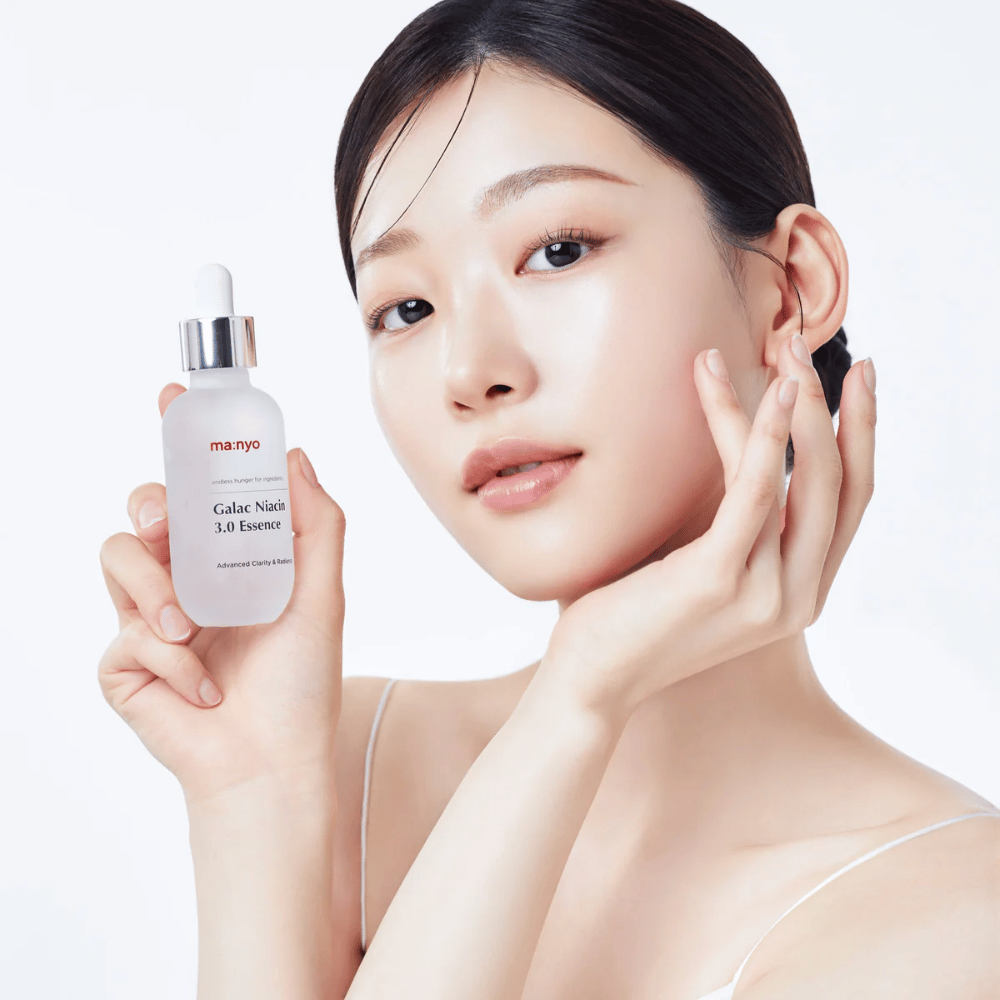 Femme à la peau éclatante tenant Ma:nyo Galac Niacin 3.0 Essence – essence coréenne qui offre un teint plus uniforme et une luminosité naturelle.