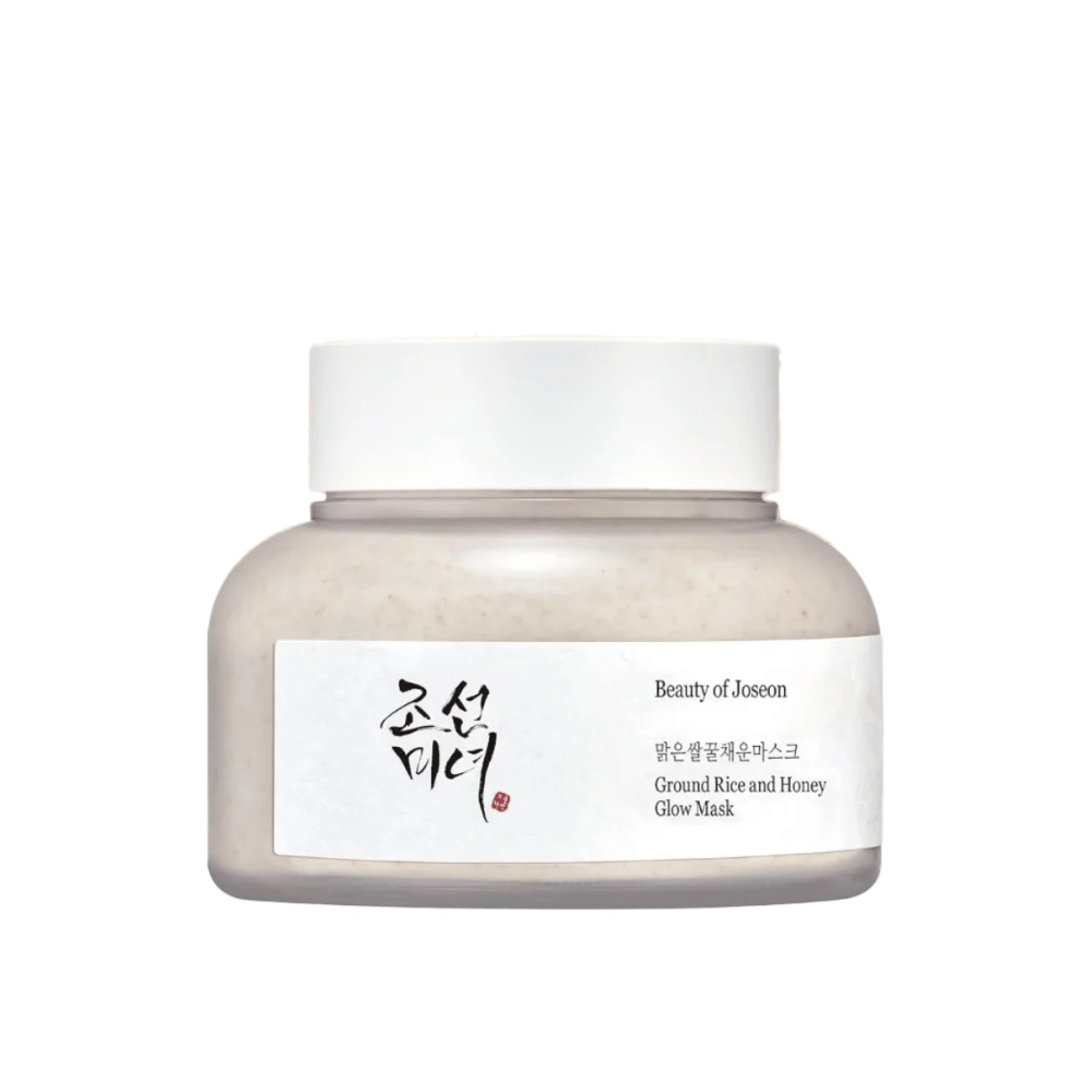 Un pot "Beauty of Joseon Ground Rice and Honey Glow Mask". L'emballage est simple avec un bouchon blanc et une étiquette qui présente le nom du produit et les ingrédients en coréen et en anglais. Le produit est conçu pour donner de l'éclat et nourrir la peau.