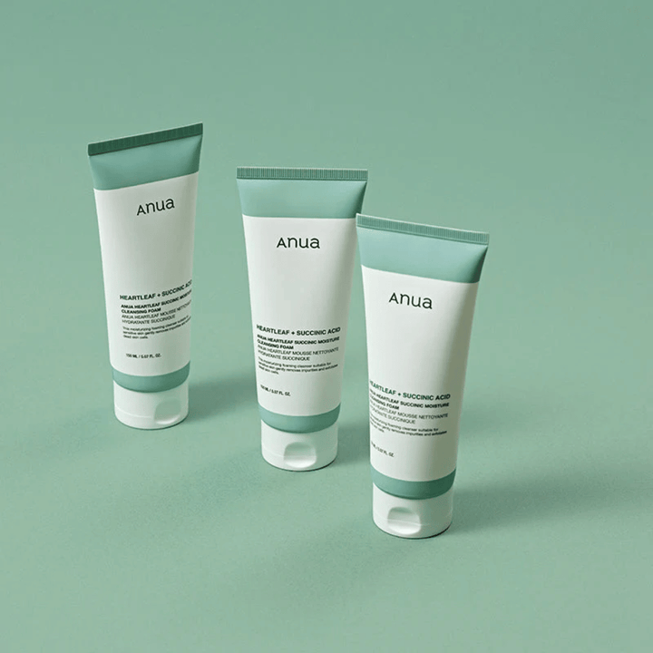 Trois emballages de Anua Heartleaf + Succinic Acid Moisture Cleansing Foam présentés sur un fond vert clair. L’image met en avant le design propre et minimaliste du produit tout en donnant une impression professionnelle de la gamme de produits.