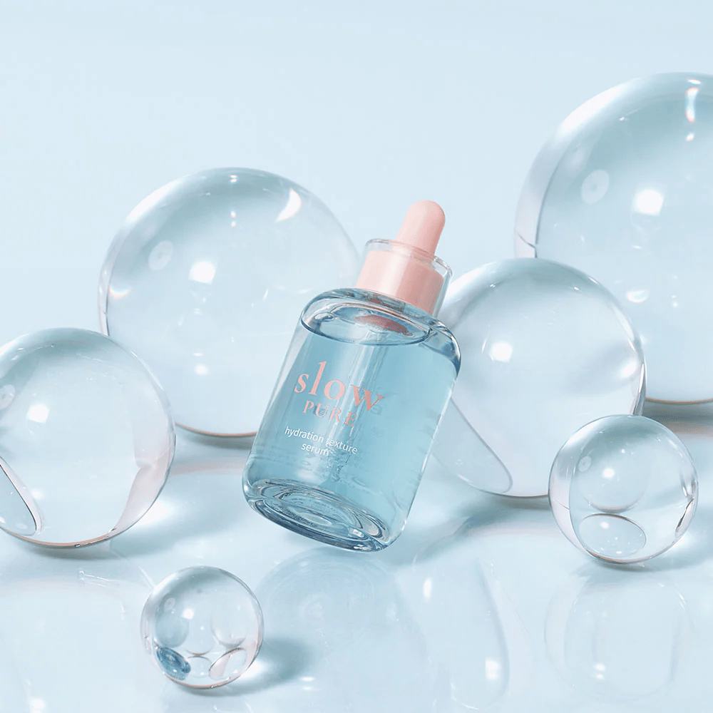 Slow Pure Hydration Texture Serum placerad bland genomskinliga bubblor, symbol för intensiv återfuktning.