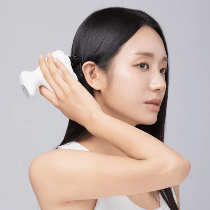 Le modèle utilise Beaund Lift Head Spa directement sur le cuir chevelu derrière l’oreille. L’image montre comment l’appareil est utilisé pour masser le cuir chevelu et procurer une stimulation agréable.