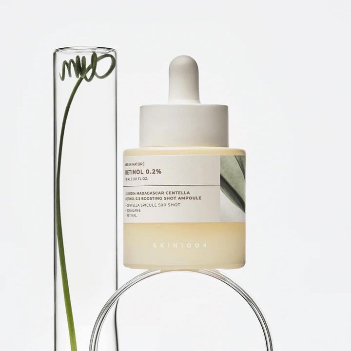 SKIN1004 Madagascar Centella Retinol 0.2 Boosting Shot Ampoule dans une image de style de vie avec des éléments botaniques – sérum visage qui soutient le renouvellement de la peau et renforce la barrière cutanée.