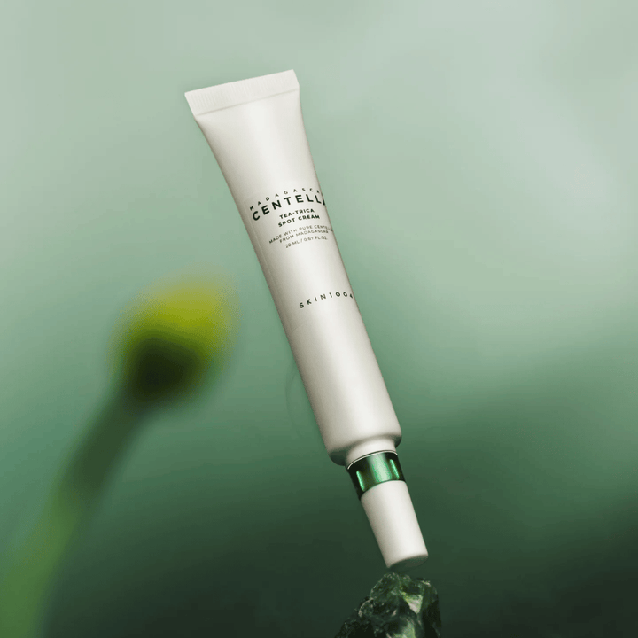 SKIN1004 Madagascar Centella Tea-Trica Spot Cream flottant sur fond vert – traitement localisé efficace treatment pour les peaux sujettes à l'acné avec centella de Madagascar.