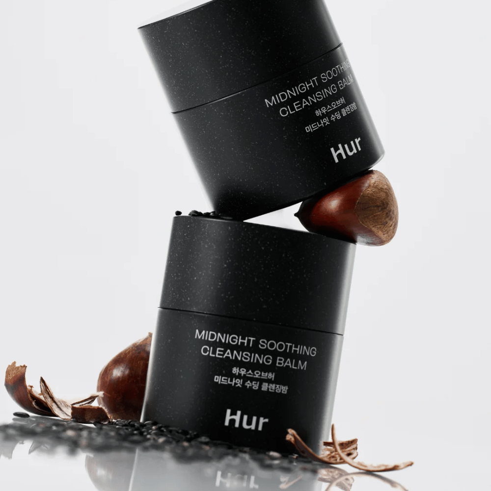 Deux pots Comment Midnight Soothing Cleansing Balm empilés avec des ingrédients naturels. Baume nettoyant nourrissant pour le nettoyage quotidien des peaux sensibles.