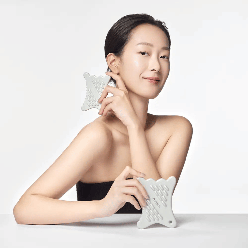 Modèle utilisant RETURNITY Mini Guasha le long de la mâchoire pour un massage du visage et une routine de soin de la peau.