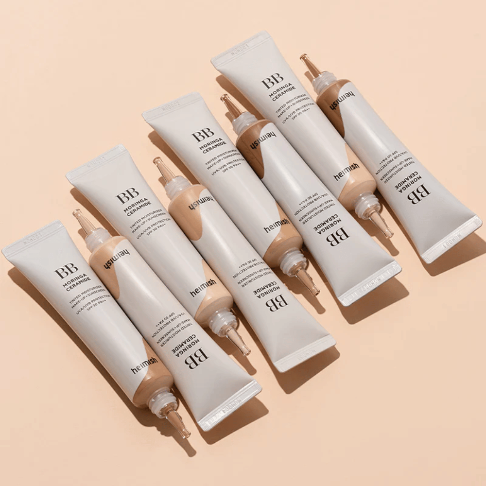 Plusieurs tubes de Heimish Moringa Ceramide BB Cream disposés sur un fond beige clair. L’image met en avant les différentes nuances et le design d’emballage élégant et minimaliste du produit.