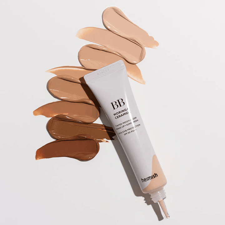 Heimish Moringa Ceramide BB Cream entouré de plusieurs échantillons de teinte dans différents tons de peau. L’image montre la large gamme de couleurs du produit et la texture crémeuse qui offre une couvrance naturelle et un teint uniforme.