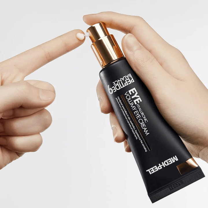 Application du MEDI-PEEL Peptide 9 Hyaluronic Volumy Eye Cream sur le bout des doigts – crème contour des yeux hydratant avec complexe de peptides qui aide à réduire les ridules et à donner une peau repulpée.