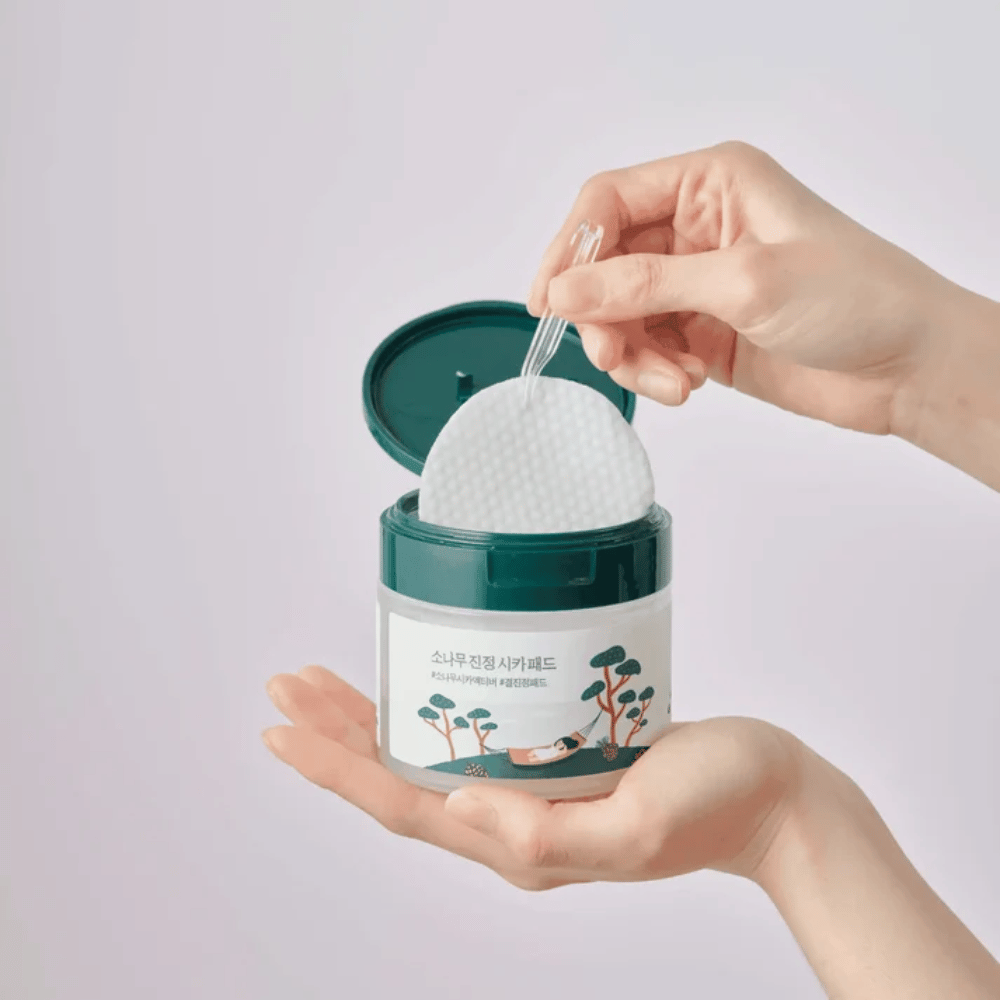 ROUND LAB Pine Calming Cica Pad – un pad toner visage est retiré du pot avec la pince fournie