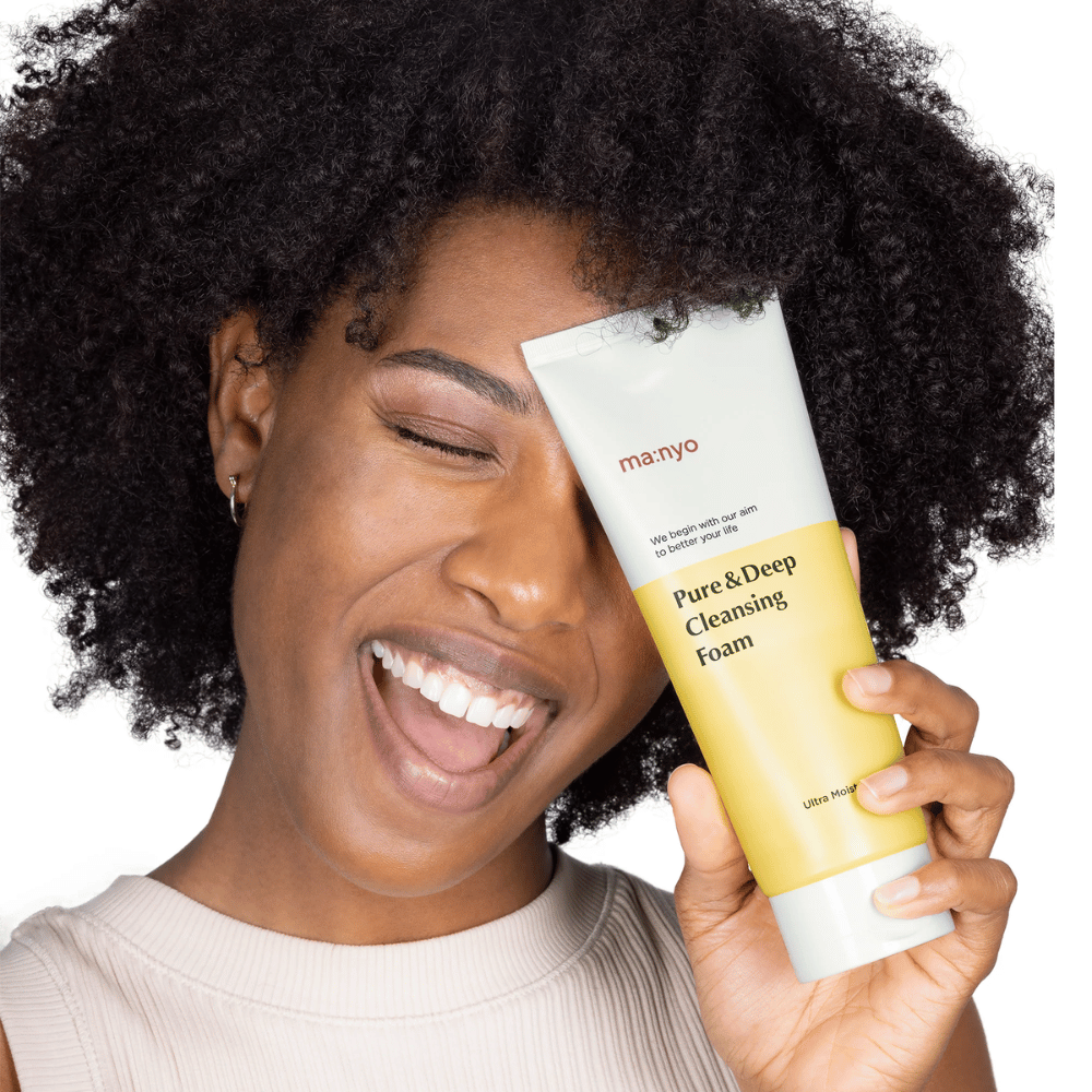 Femme aux cheveux bouclés tenant Ma:nyo Pure & Deep Cleansing Foam – un nettoyant coréen doux qui élimine efficacement la saleté et le maquillage sans dessécher la peau.