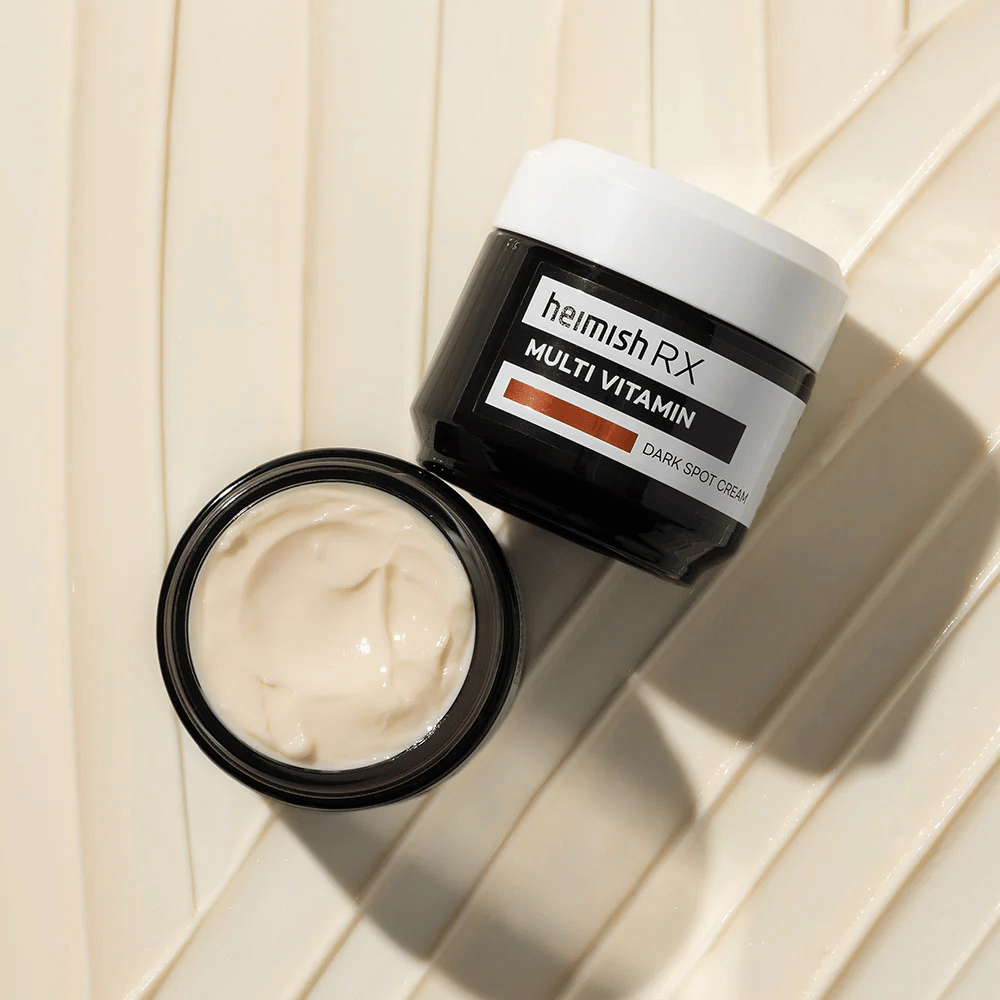 heimish RX Multi Vitamin Dark Spot Cream - une crème pour le visage nutritive pour réduire les taches sombres et donner à la peau un teint plus uniforme. La texture douce de la crème est montrée dans un pot ouvert avec un emballage élégant.