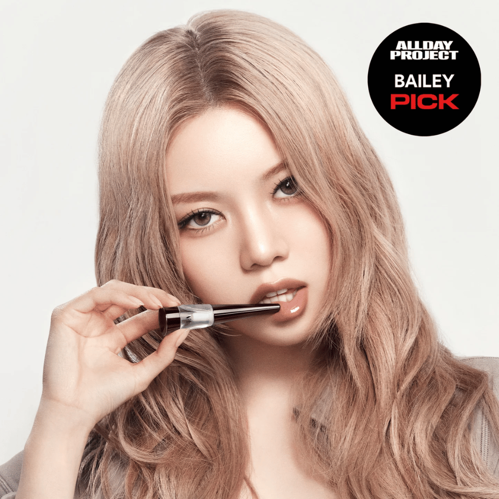 Modèle appliquant VT Reedle Shot Lip Plumper Expert sur les lèvres, finition brillante et lèvres plus pulpeuses, marqué comme Bailey Pick du projet All Day.