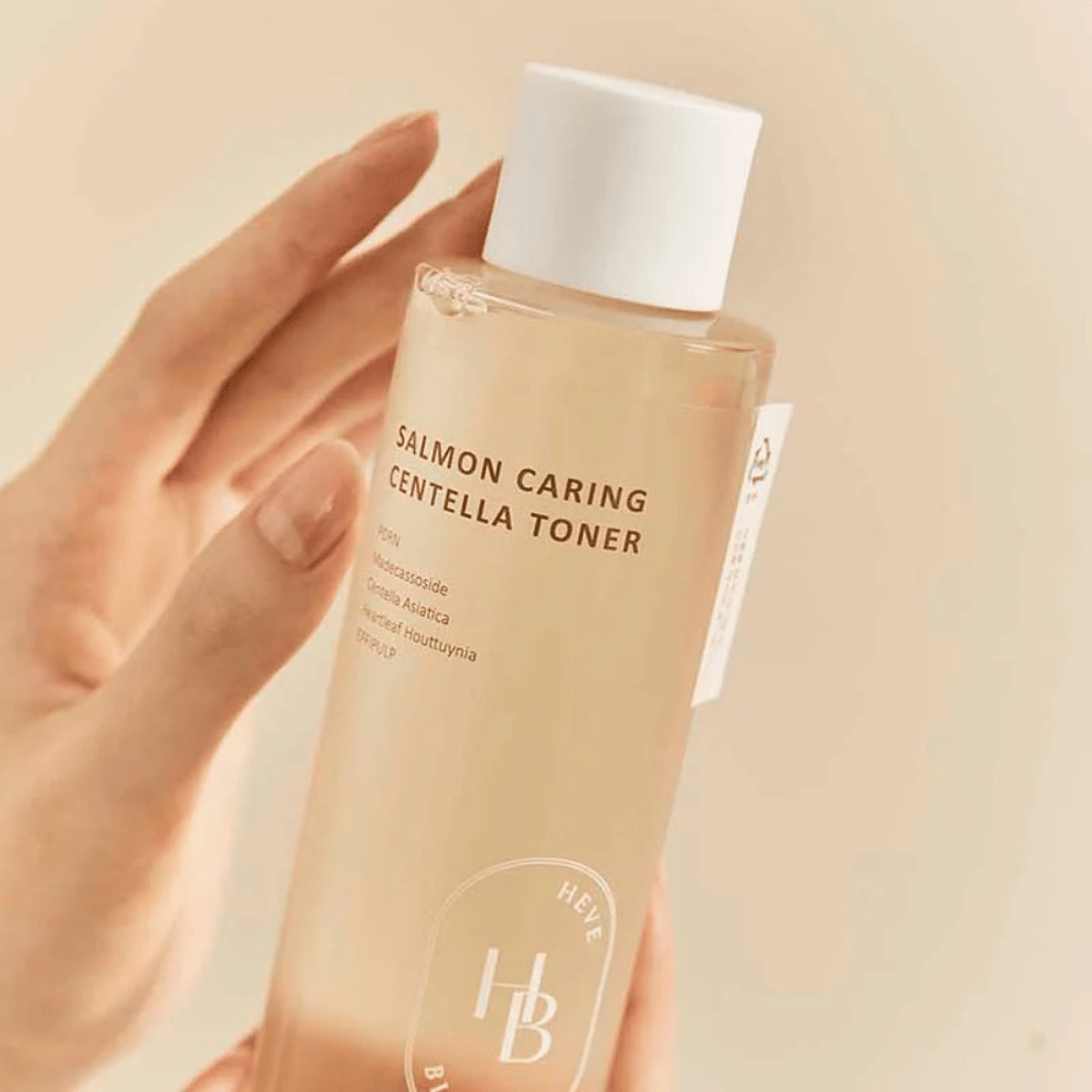 Gros plan de Salmon Caring Centella Toner dans la main – apaisant toner visage avec PDRN et extrait de plante qui aide à renforcer la peau et à réduire la sensation d'irritation.