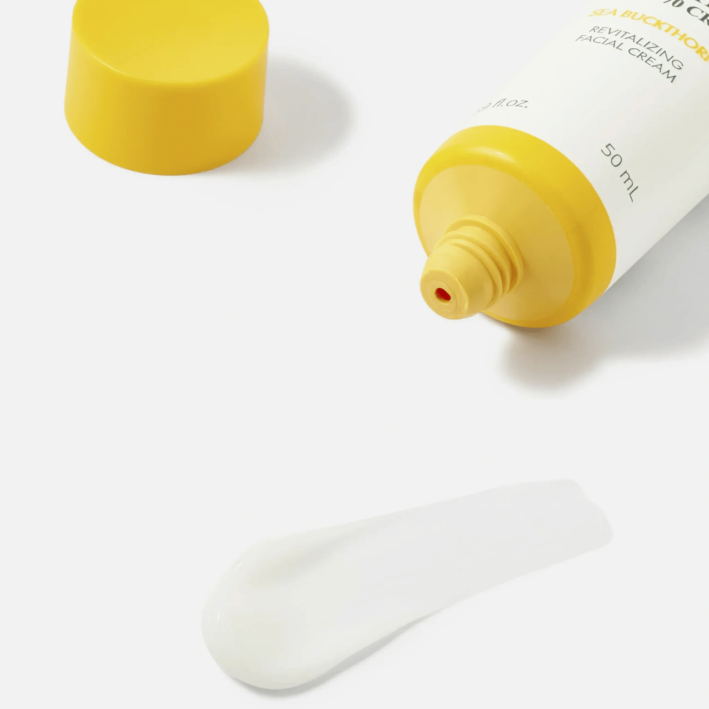 1. Purito SEOUL Sea Buckthorn Vital 70 Cream – gros plan sur la texture blanche légère de la crème pour le visage à côté d’un tube ouvert avec bouchon jaune