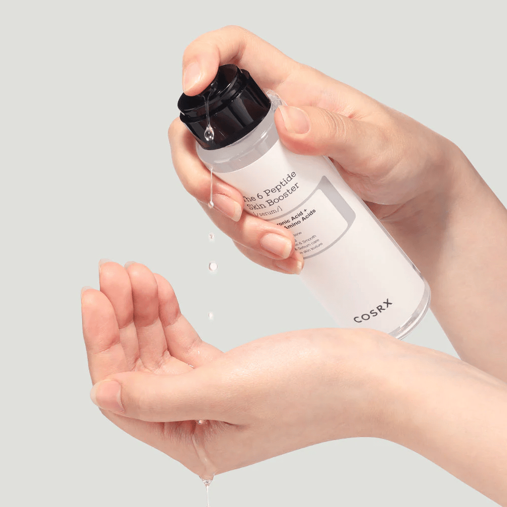 Mains versant un produit de soin de la peau d'une bouteille transparente avec le texte "The Peptide Skin Booster".