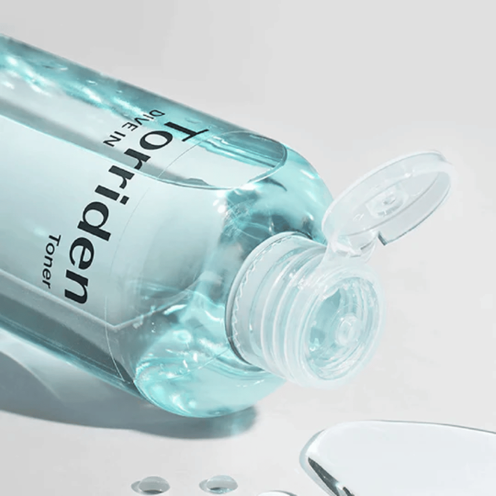 Une bouteille DIVE-IN Low Molecule Hyaluronic Acid Toner 300ml à côté d'un verre d'eau, favorise Torriden et l'hydratation.