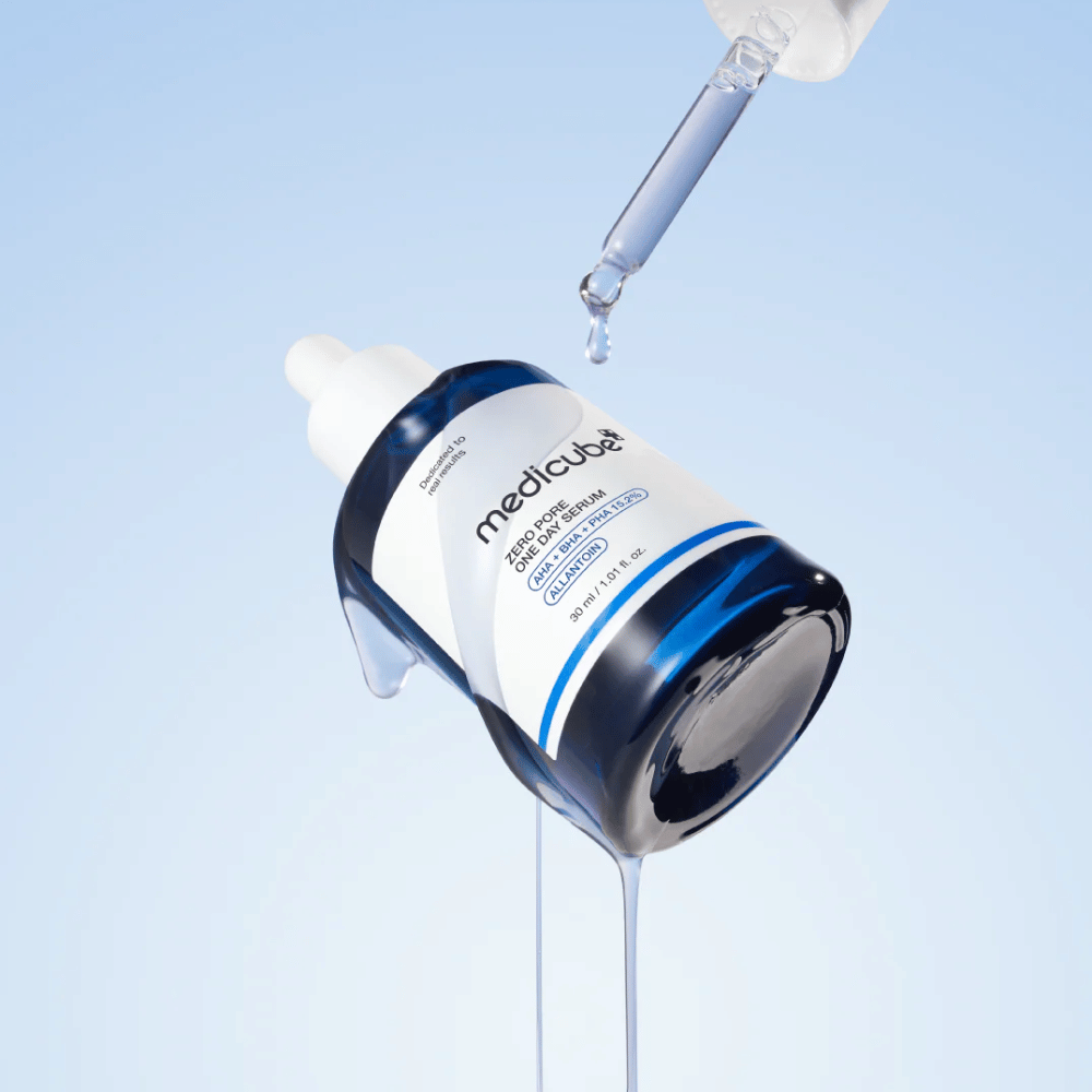Bouteille de Medicube Zero Pore One Day Serum avec pipette et gouttes de sérum s'écoulant sur un fond bleu clair.
