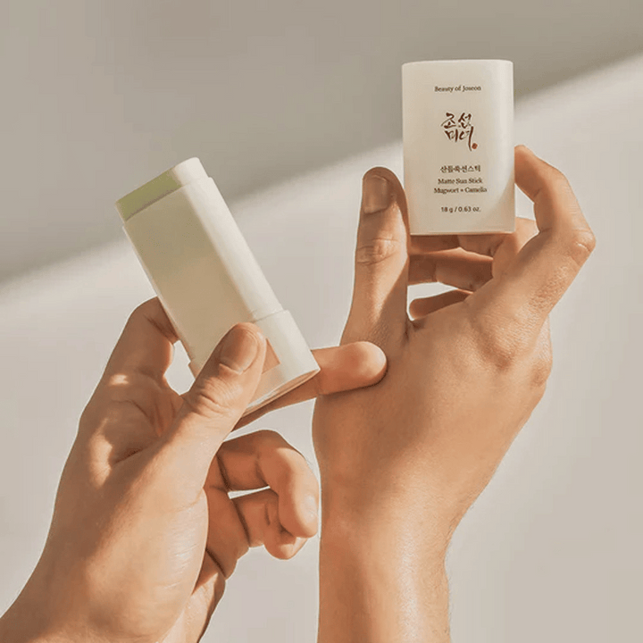 Två händer som håller en sticka av Beauty of Joseon's Matte Sun Stick 18g SPF50 PA++++.